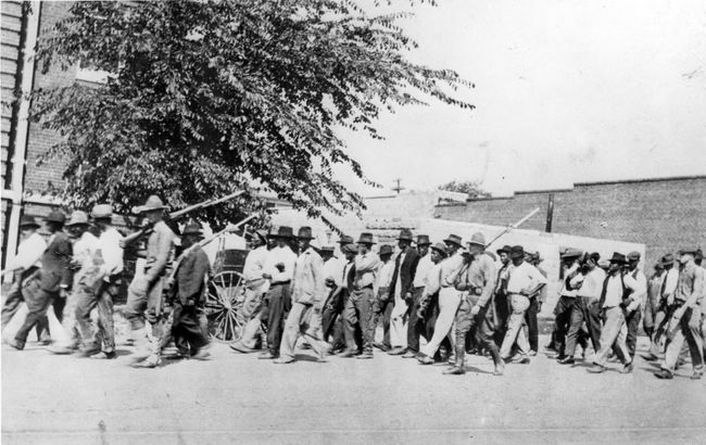 Grupa pripadnika Nacionalne garde, noseći puške s pričvršćenim bajunetama, prati nenaoružane crnce u zatočenički centar nakon masakra u utrci u Tulsi, Tulsa, Oklahoma, lipanj 1921.