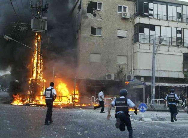 Izraelski policajci pohrlili su na mjesto zapaljenog električnog stuba i oštećene zgrade nekoliko trenutaka nakon što je odbojnica raketa Hezbollah pogodila 13. srpnja 2006. u sjevernom gradu Nahariya u Izraelu.