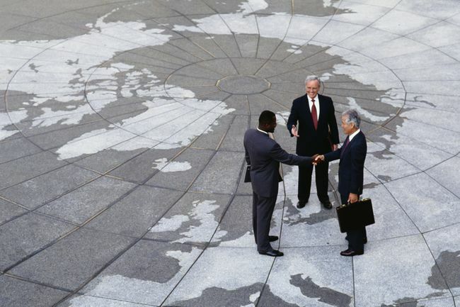  Ekonomski regionalizam: Poslovni ljudi se rukuju na karti svijeta.