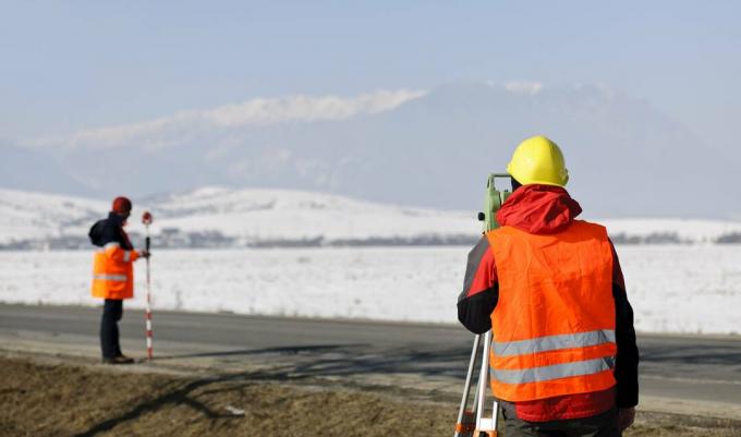 geodetski radnik koji radi u zimskom polju