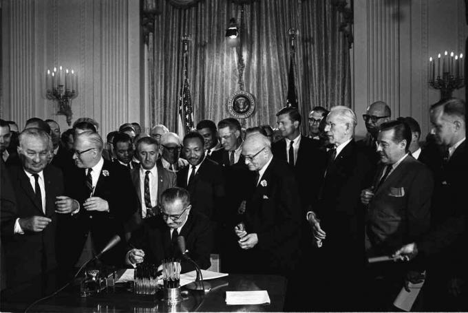 Predsjednik Lyndon B. Johnson potpisuje Zakon o građanskim pravima iz 1964. kao što to gledaju Martin Luther King, Jr. i drugi.